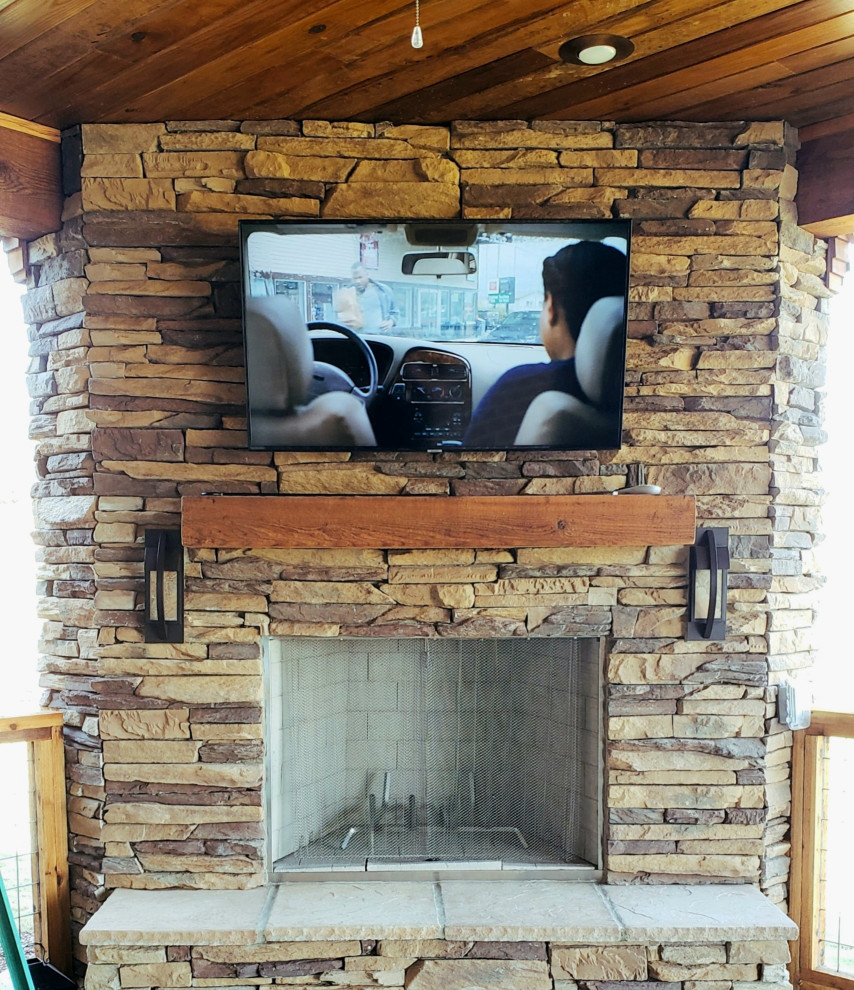 Immagine di un piccolo portico american style dietro casa con un caminetto, cemento stampato, un tetto a sbalzo e parapetto in materiali misti