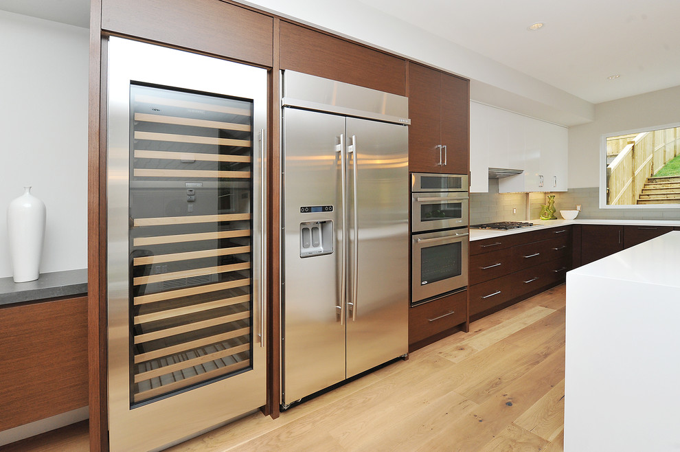 Example of a large transitional l-shaped medium tone wood floor eat-in kitchen design in Calgary with an undermount sink, flat-panel cabinets, medium tone wood cabinets, gray backsplash, stainless steel appliances and an island