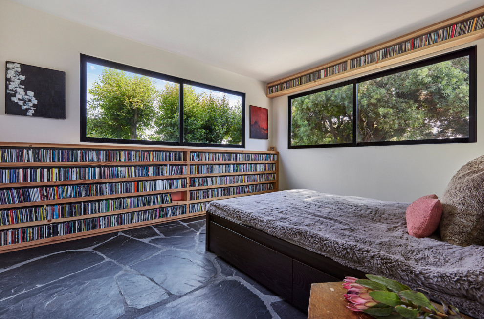 Imagen de habitación de invitados moderna de tamaño medio sin chimenea con paredes blancas, suelo de pizarra, suelo negro y madera