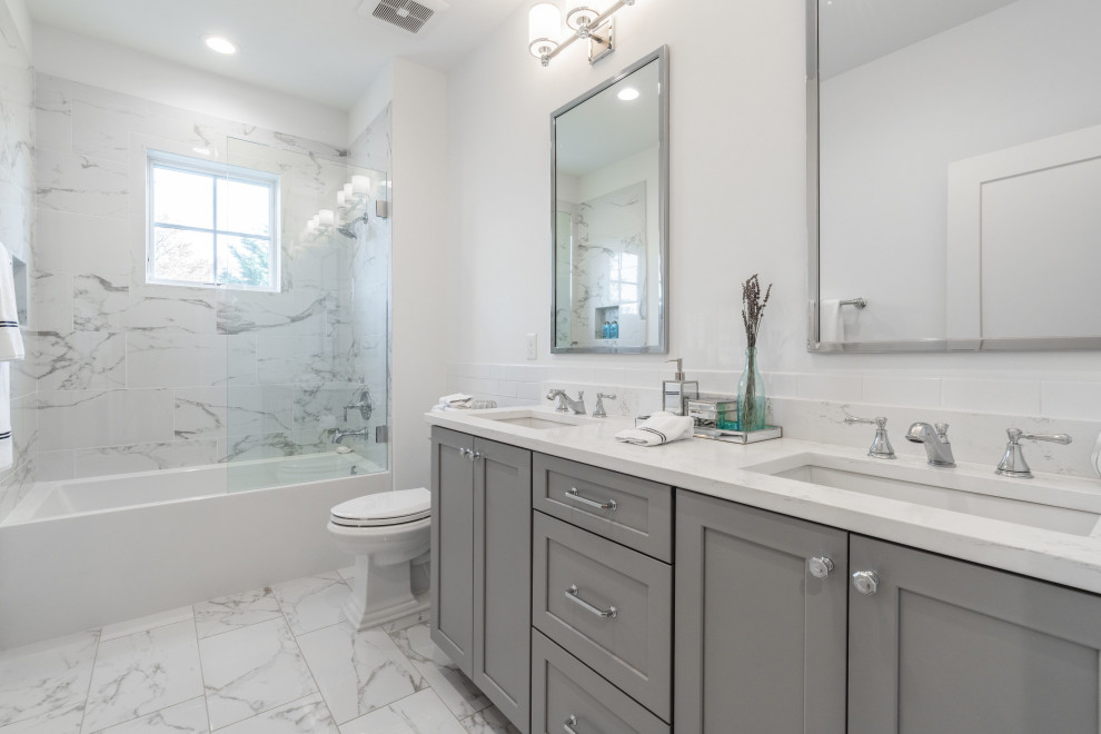 Inspiration for a large transitional 3/4 bathroom in DC Metro with shaker cabinets, grey cabinets, an alcove tub, a shower/bathtub combo, a two-piece toilet, gray tile, white tile, porcelain tile, white walls, porcelain floors, an undermount sink, grey floor, white benchtops, a double vanity and a built-in vanity.