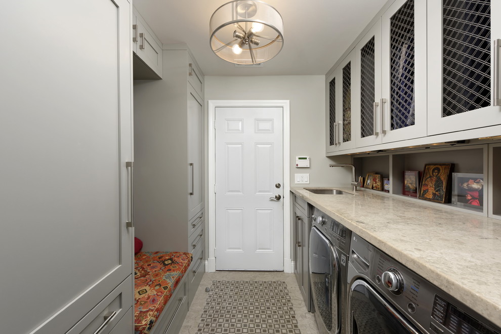 Photo of a mid-sized transitional galley utility room in DC Metro with an undermount sink, shaker cabinets, grey cabinets, limestone benchtops, grey walls, marble floors, a side-by-side washer and dryer, grey floor and grey benchtop.