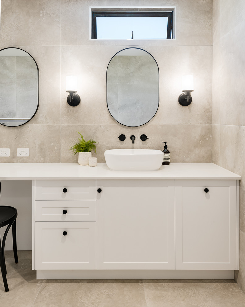 This is an example of a large contemporary master bathroom in Brisbane with shaker cabinets, white cabinets, a drop-in tub, a double shower, a one-piece toilet, beige tile, porcelain tile, beige walls, porcelain floors, a console sink, solid surface benchtops, beige floor, an open shower and beige benchtops.