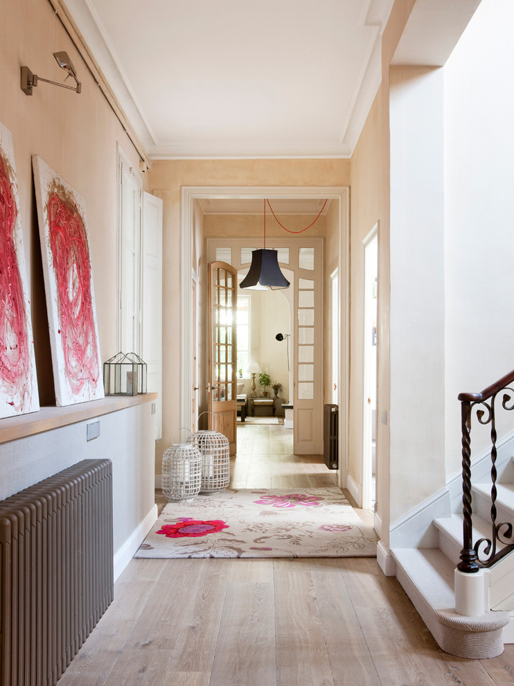Inspiration for a mid-sized transitional hallway in Barcelona with beige walls and light hardwood floors.