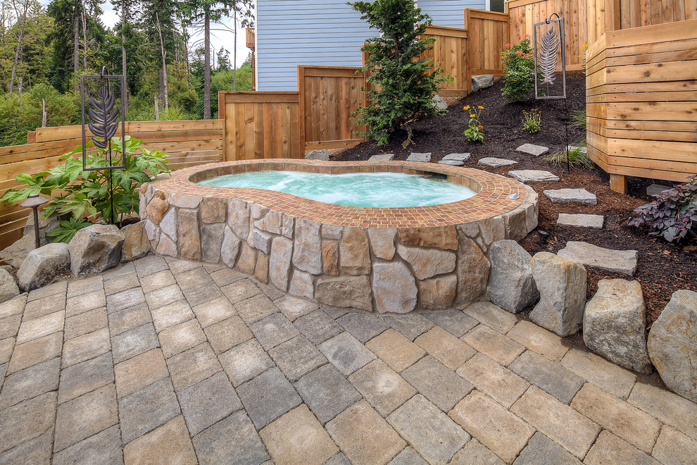 Large traditional backyard kidney-shaped pool in Portland with a hot tub and concrete pavers.