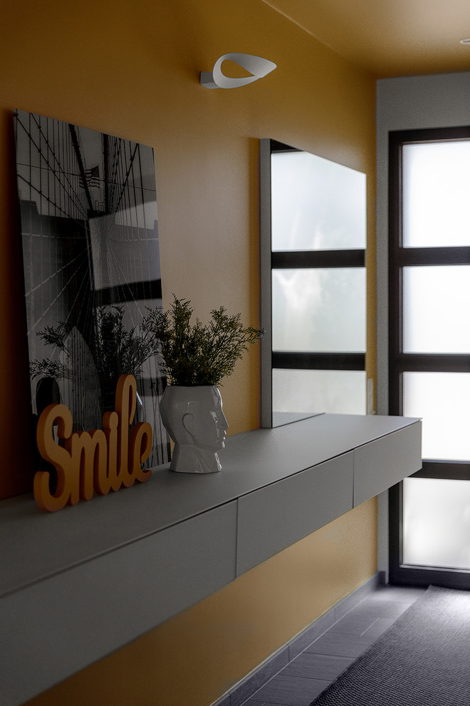 Trendy ceramic tile and gray floor foyer photo with yellow walls and a black front door