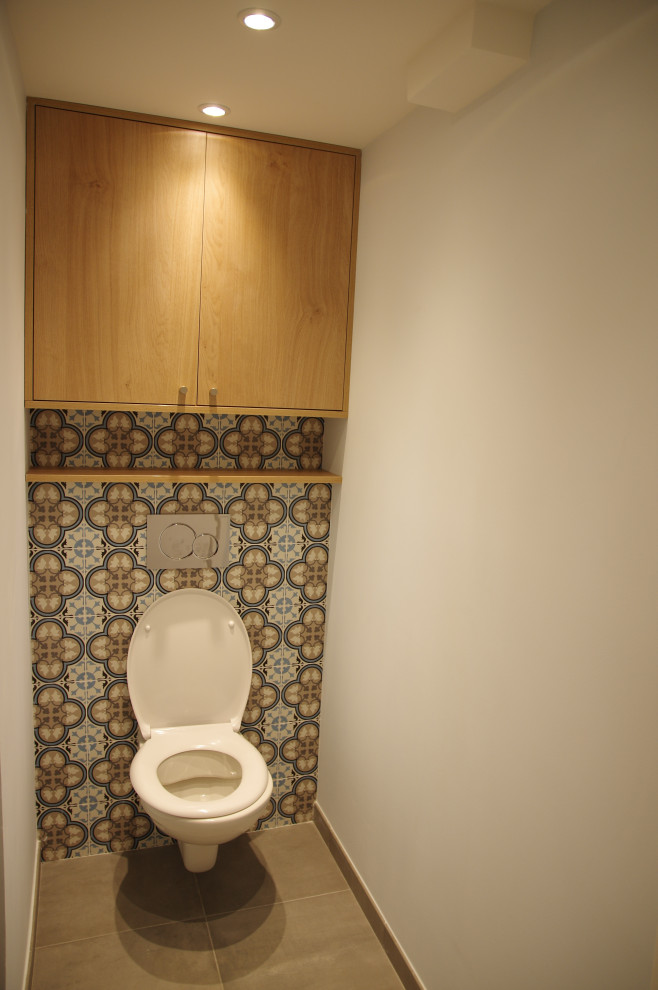 リヨンにある低価格の小さなコンテンポラリースタイルのおしゃれなトイレ・洗面所 (壁掛け式トイレ、マルチカラーのタイル、セメントタイル、コンクリートの床、グレーの床) の写真
