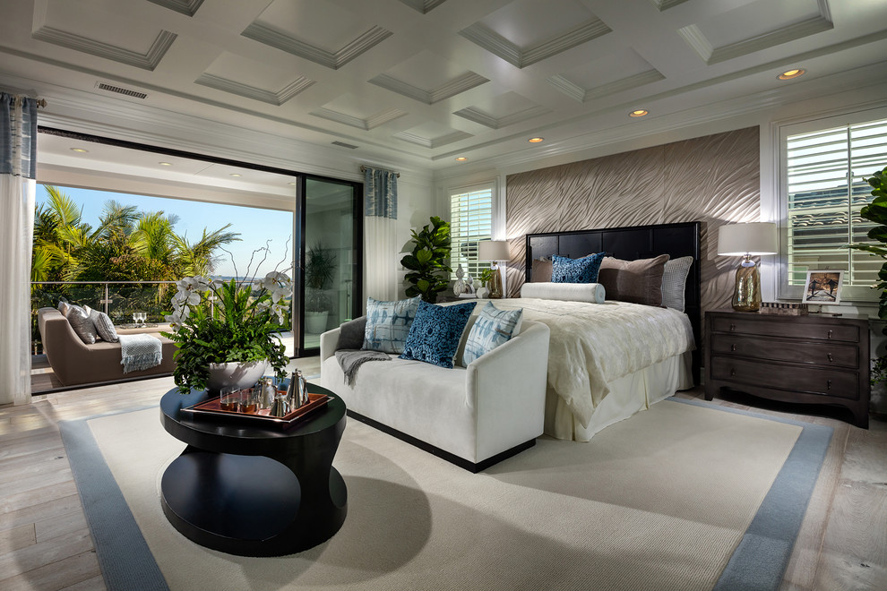Photo of an expansive tropical master bedroom in San Diego with light hardwood floors, no fireplace and beige walls.