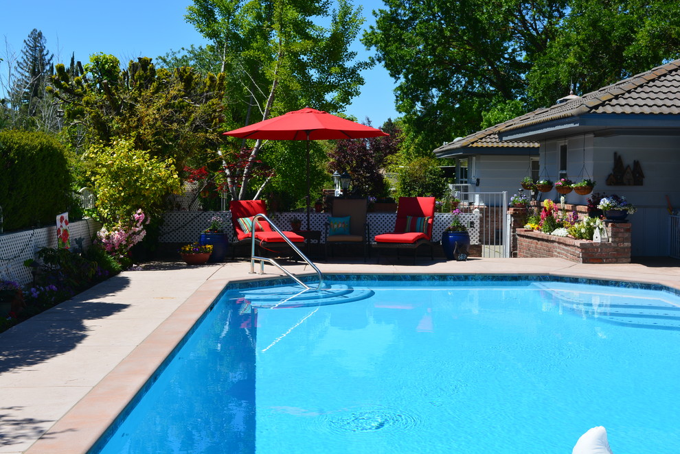Large traditional side yard custom-shaped pool in Sacramento with stamped concrete.
