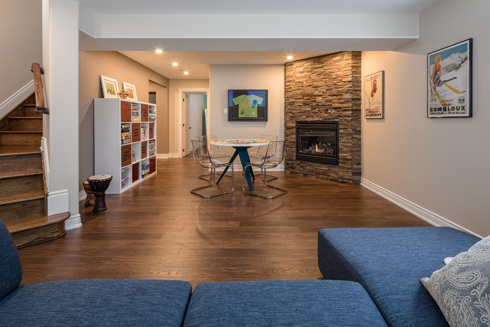 Mid-sized transitional look-out basement in Ottawa with beige walls, a corner fireplace, a stone fireplace surround and laminate floors.