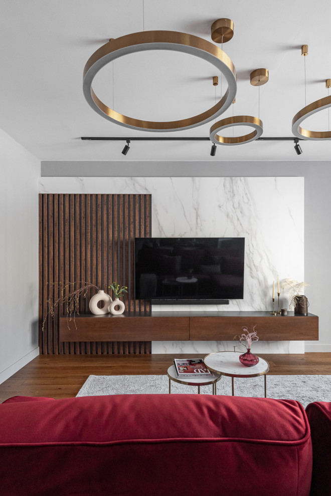 На фото: серо-белая гостиная комната среднего размера в современном стиле с серыми стенами, паркетным полом среднего тона, телевизором на стене, коричневым полом и бордовым диваном без камина с