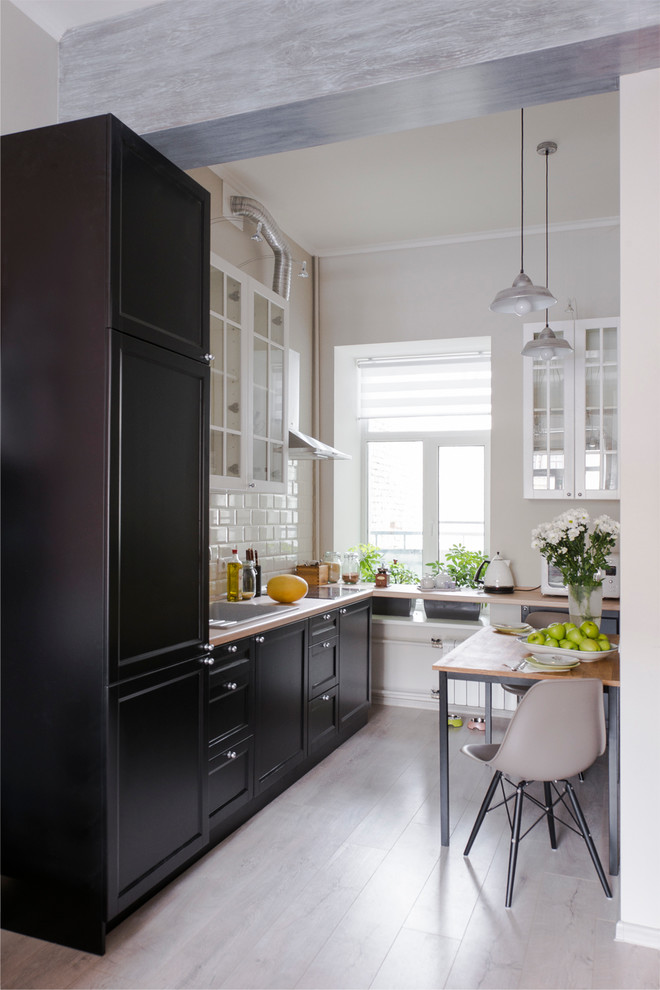 Inspiration for a small traditional single-wall eat-in kitchen in Moscow with an undermount sink, black cabinets, white splashback, ceramic splashback, black appliances, medium hardwood floors and no island.