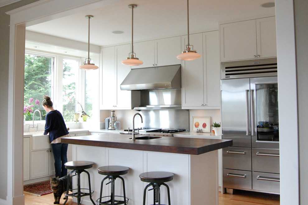 Photo of a traditional l-shaped kitchen in Seattle with a farmhouse sink, wood benchtops and stainless steel appliances.