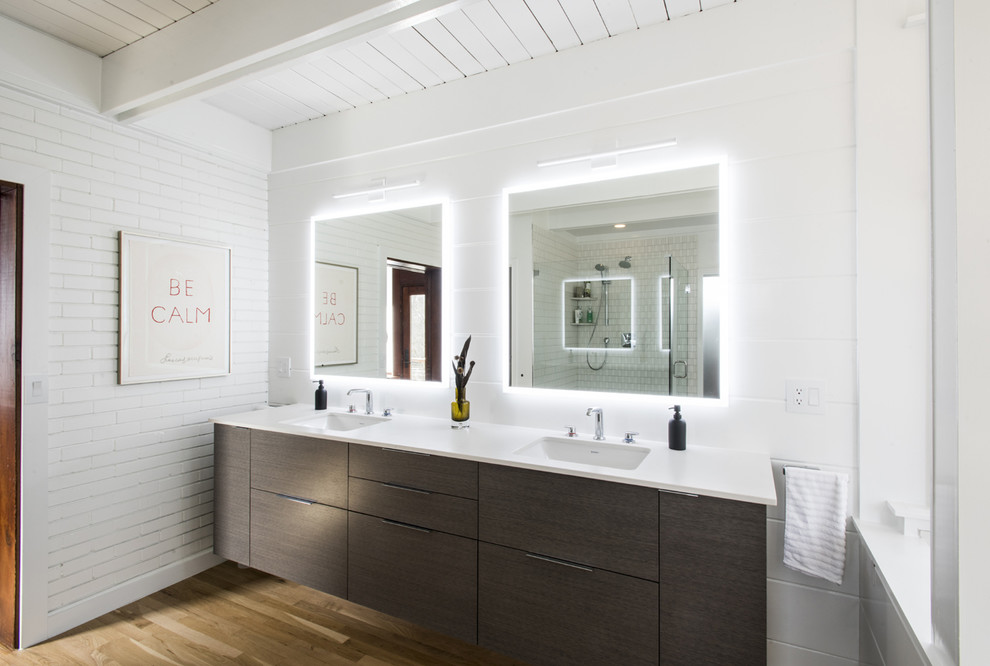 Inspiration for a midcentury master bathroom in Louisville with flat-panel cabinets, grey cabinets, a freestanding tub, white tile, white walls, medium hardwood floors, an undermount sink, engineered quartz benchtops and white benchtops.