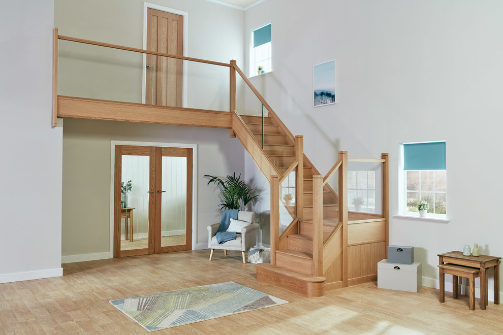 This is an example of a mid-sized transitional wood u-shaped staircase in Manchester with wood risers and glass railing.
