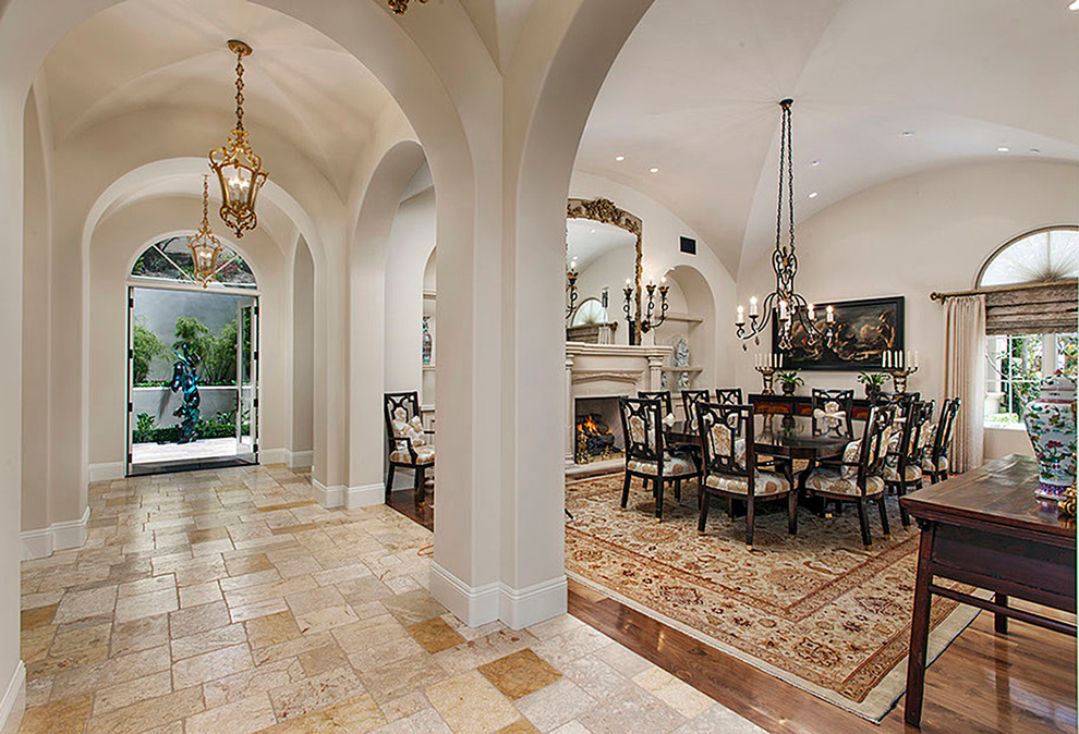 Photo of a large mediterranean open plan dining in Orange County with beige walls, limestone floors, a standard fireplace and a stone fireplace surround.