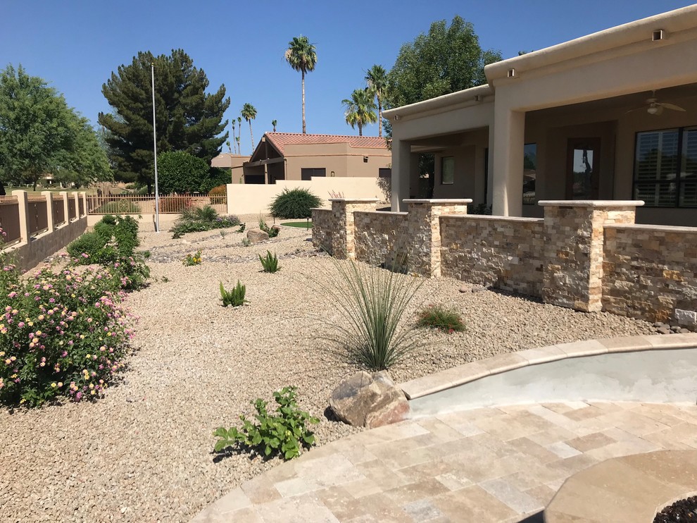 Large traditional backyard full sun xeriscape in Phoenix with a retaining wall and natural stone pavers.