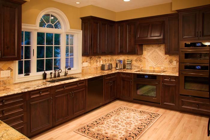 Inspiration for a traditional eat-in kitchen in Minneapolis with an undermount sink, flat-panel cabinets, dark wood cabinets, granite benchtops, stone tile splashback and coloured appliances.