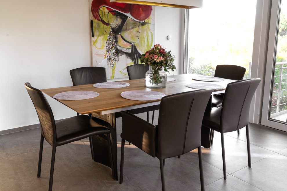 This is an example of a mid-sized contemporary separate dining room in Stuttgart with white walls, concrete floors, no fireplace and grey floor.