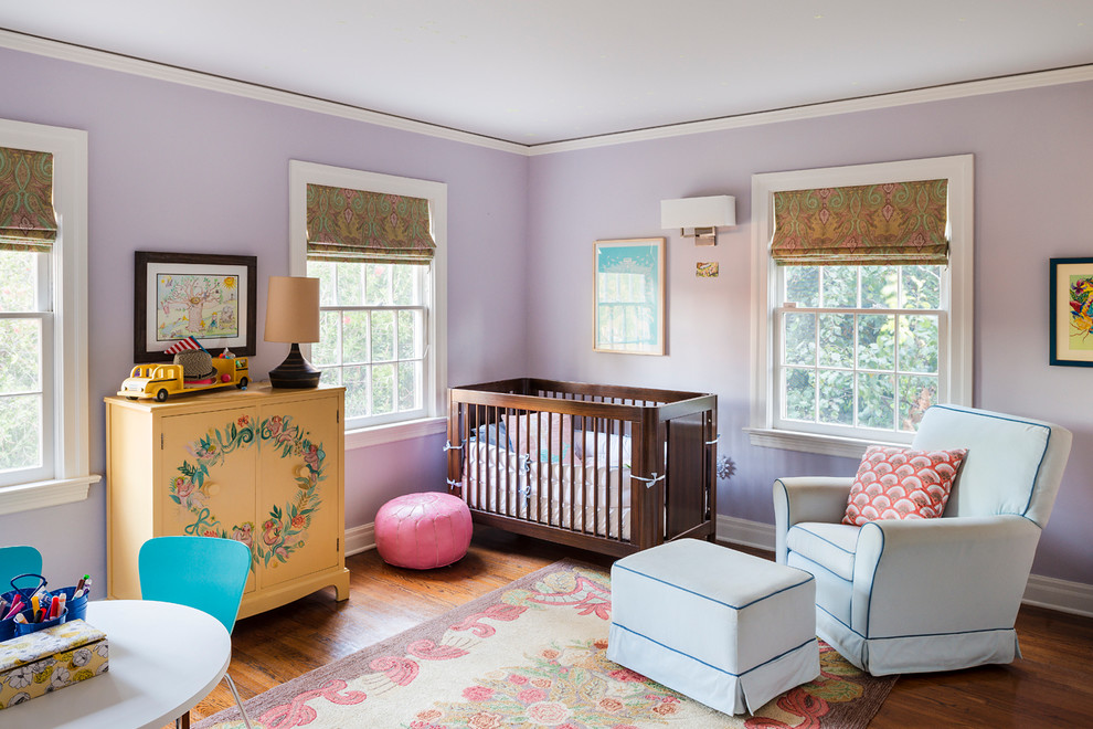 Design ideas for a mid-sized transitional nursery for girls in Los Angeles with purple walls, medium hardwood floors and brown floor.