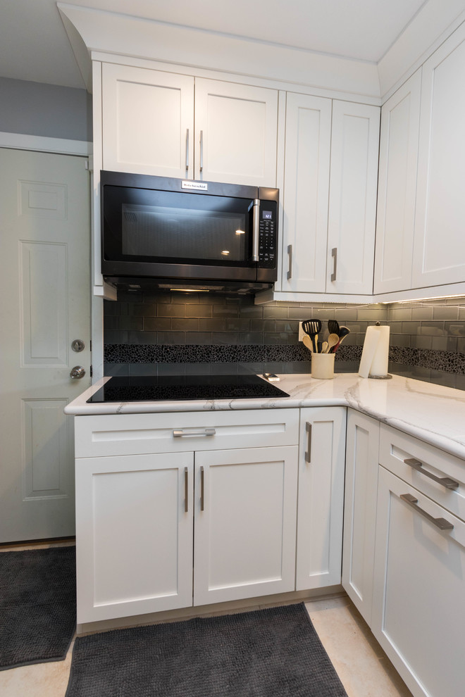 Mid-sized transitional galley ceramic tile open concept kitchen photo in Miami with a single-bowl sink, shaker cabinets, white cabinets, quartz countertops, black backsplash, glass tile backsplash, black appliances and a peninsula
