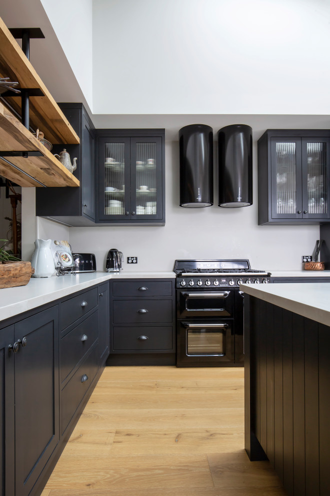 Inspiration for a large traditional l-shaped open plan kitchen in Sydney with a belfast sink, shaker cabinets, black cabinets, engineered stone countertops, white splashback, engineered quartz splashback, black appliances, light hardwood flooring, an island, white worktops and a vaulted ceiling.