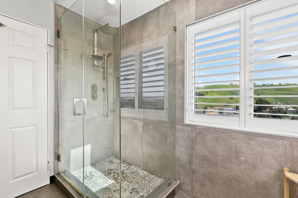 Inspiration for a mid-sized contemporary master bathroom in Los Angeles with furniture-like cabinets, medium wood cabinets, a corner shower, gray tile, porcelain tile, grey walls, porcelain floors, concrete benchtops, grey floor and grey benchtops.