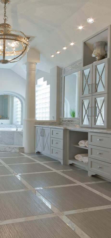 This is an example of a large contemporary master bathroom in Houston with an undermount sink, furniture-like cabinets, grey cabinets, marble benchtops, a corner tub, a curbless shower, a one-piece toilet, multi-coloured tile, porcelain tile, grey walls and porcelain floors.