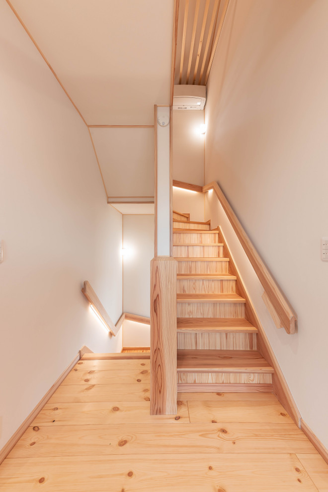 На фото: п-образная деревянная лестница среднего размера с деревянными ступенями, деревянными перилами и обоями на стенах с