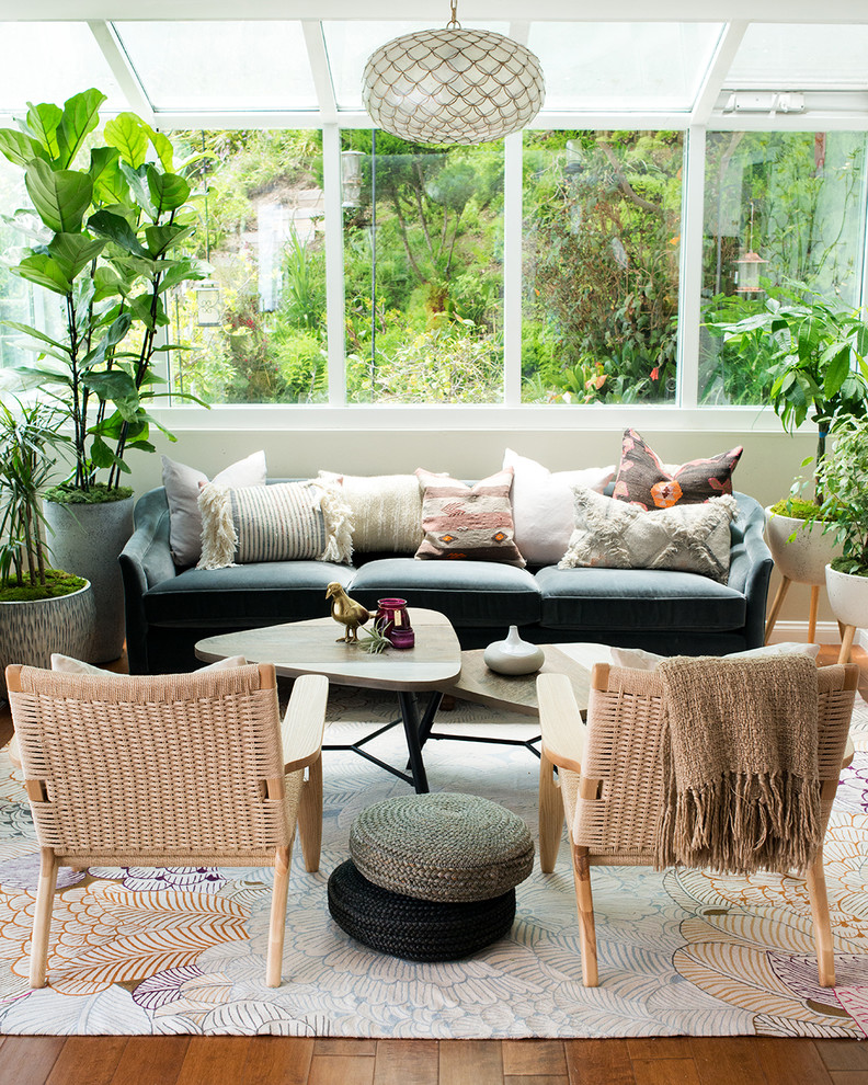 This is an example of an eclectic sunroom in Los Angeles with medium hardwood floors, a glass ceiling and brown floor.