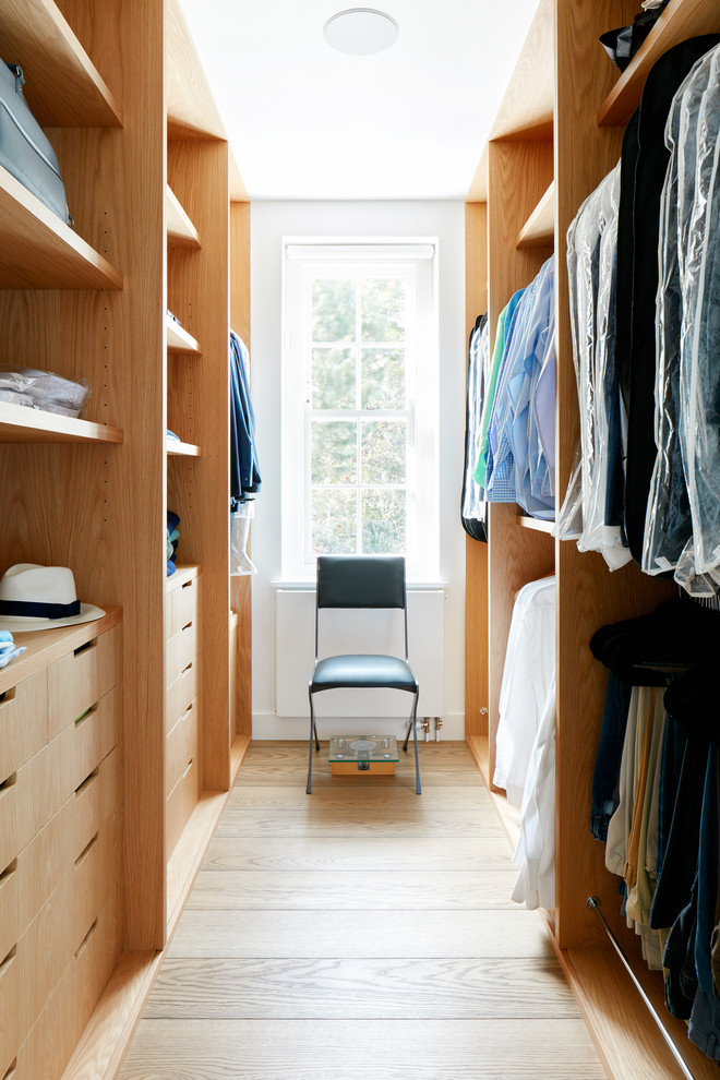 This is an example of a mid-sized contemporary gender-neutral walk-in wardrobe in London with open cabinets, light wood cabinets and light hardwood floors.