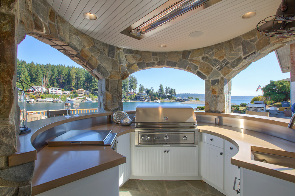 This is an example of a beach style patio in Seattle with natural stone pavers and a roof extension.