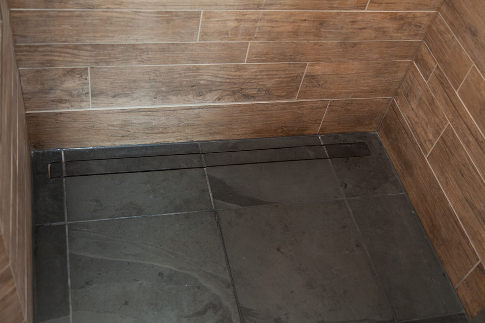 This is an example of a mid-sized country master bathroom in St Louis with a corner shower, brown tile, porcelain tile and slate floors.