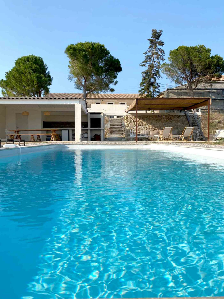 Diseño de piscina de estilo de casa de campo grande rectangular en patio delantero con gravilla
