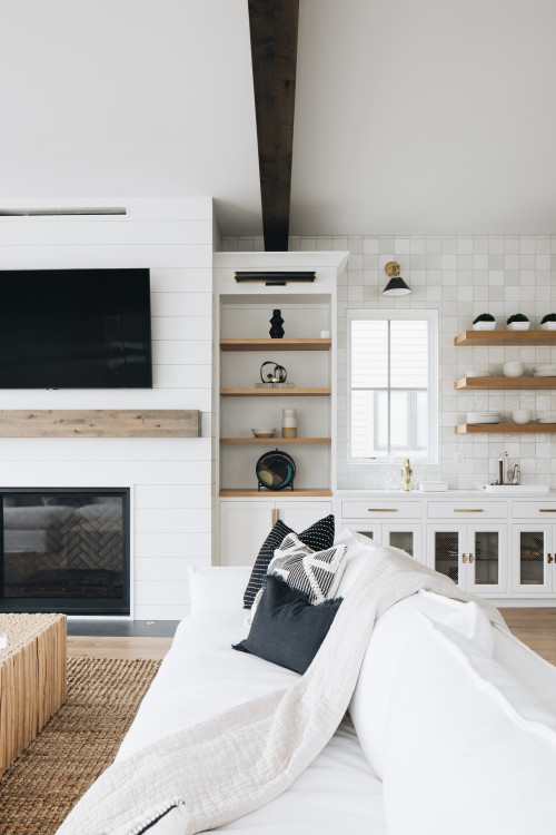 large lake house living room open concept light wood floor and exposed beam living room design in Grand Rapids with white walls, a standard fireplace, a shiplap fireplace and a wall-mounted tv 