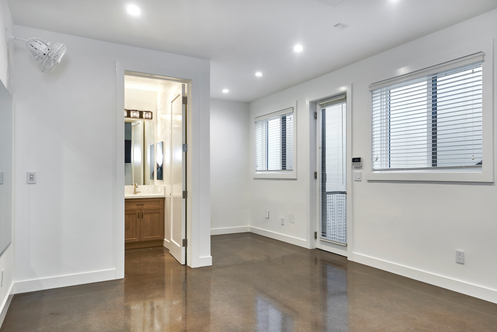 Immagine di una piccola palestra multiuso american style con pareti bianche, pavimento in cemento e pavimento marrone