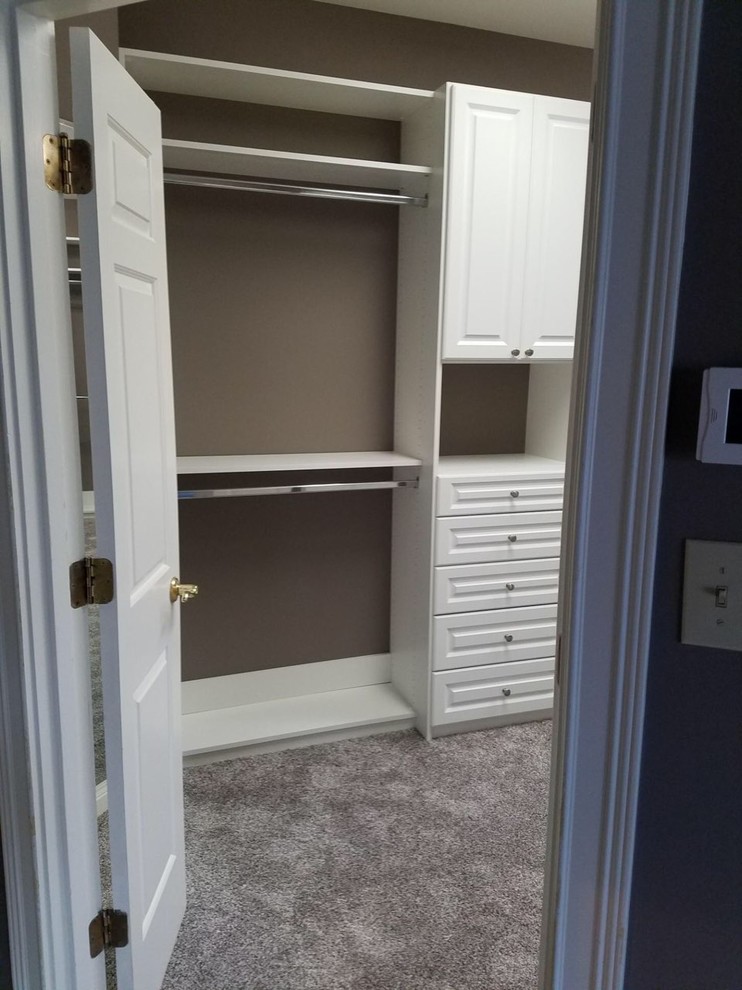 Photo of a large traditional gender-neutral walk-in wardrobe in Louisville with raised-panel cabinets, white cabinets, carpet and brown floor.