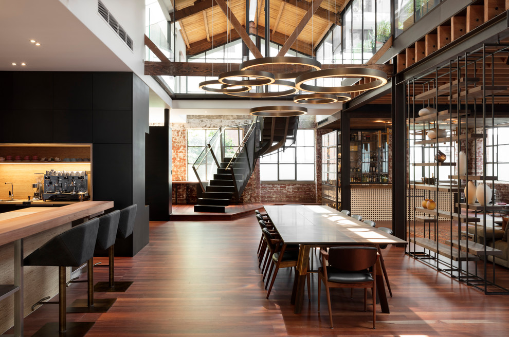 Photo of a large industrial open plan dining in Melbourne with white walls, medium hardwood floors and brown floor.