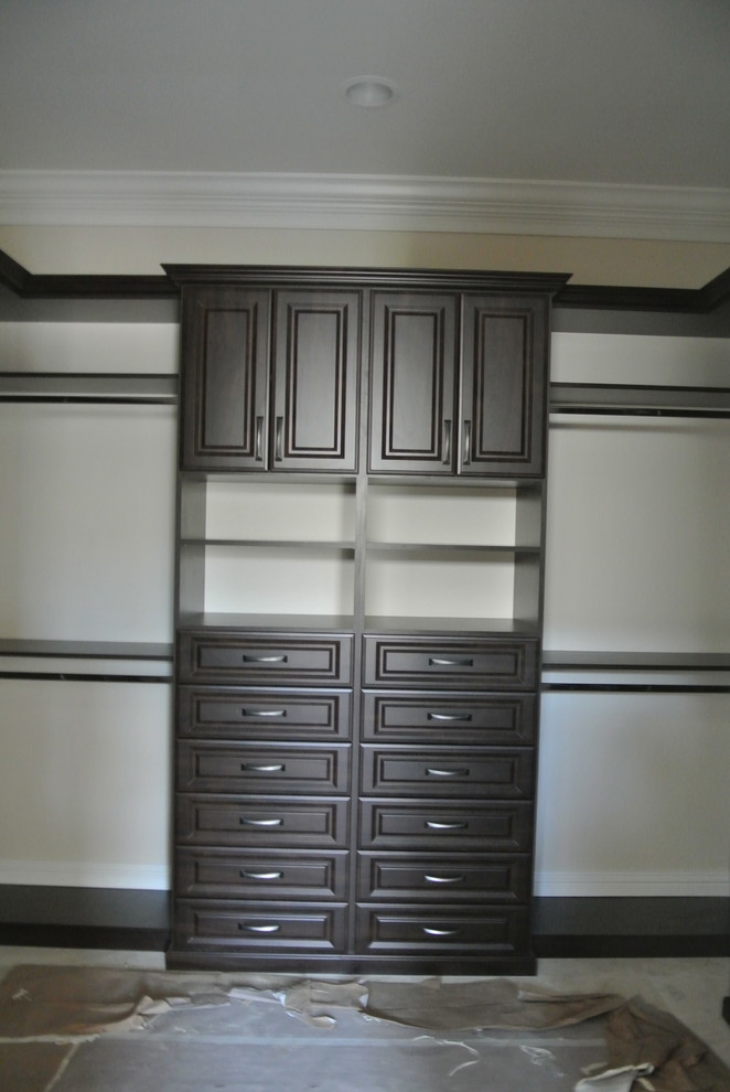 Design ideas for a large traditional gender neutral walk-in wardrobe in Miami with raised-panel cabinets, dark wood cabinets and travertine flooring.