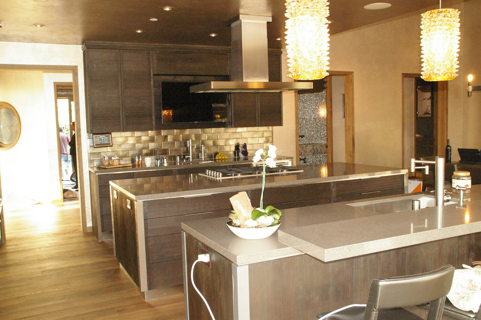 Large industrial l-shaped eat-in kitchen in Los Angeles with recessed-panel cabinets, dark wood cabinets, granite benchtops, panelled appliances and multiple islands.
