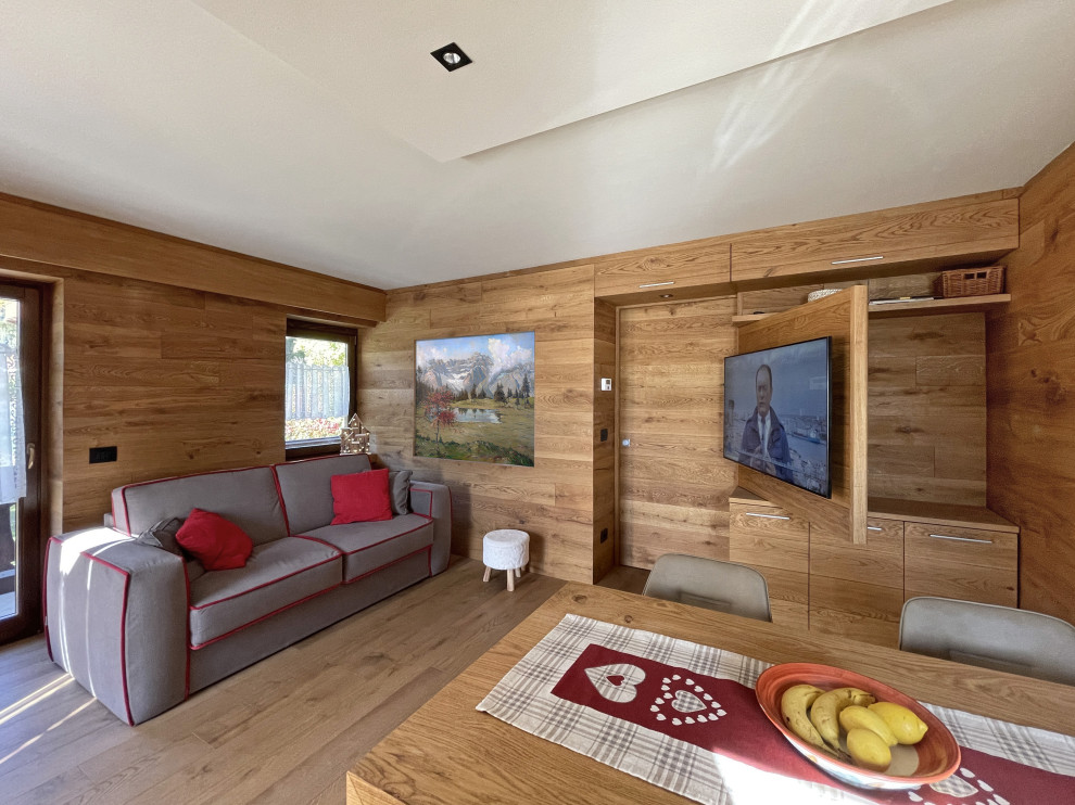 Modern inredning av ett litet allrum med öppen planlösning, med bruna väggar, ljust trägolv, en väggmonterad TV och brunt golv