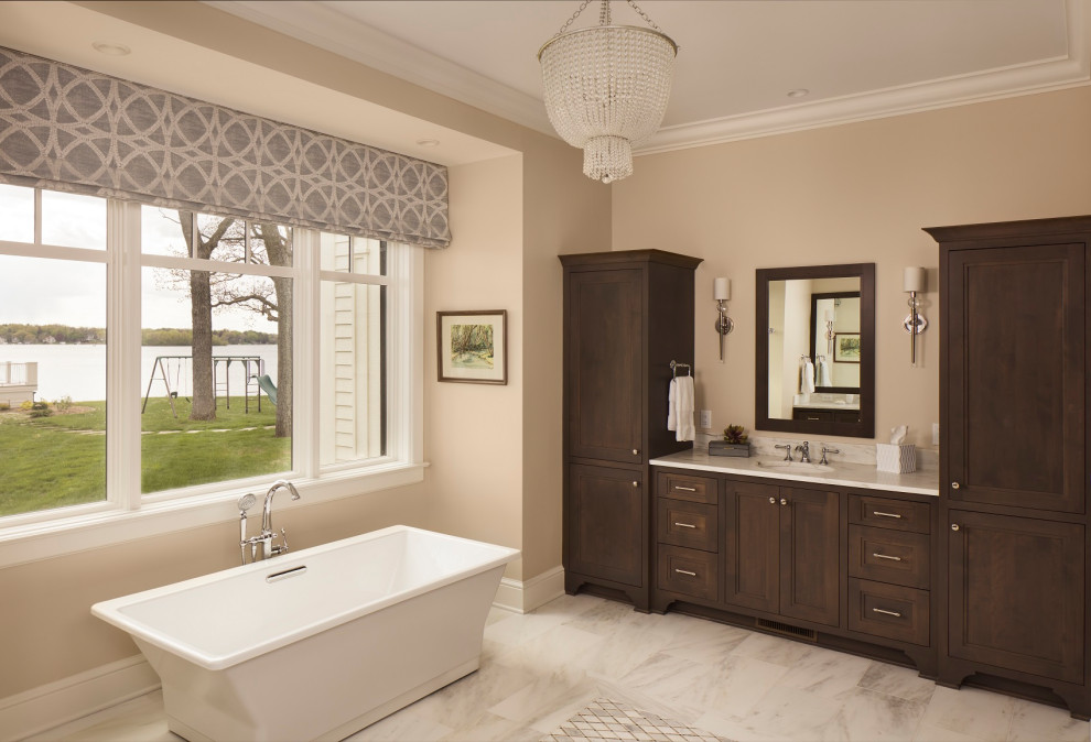 Exemple d'une grande salle de bain principale chic en bois foncé avec un placard avec porte à panneau encastré, une baignoire indépendante, une douche, du carrelage en marbre, un mur beige, un sol en carrelage de céramique, un lavabo encastré, un sol blanc, meuble simple vasque et meuble-lavabo encastré.