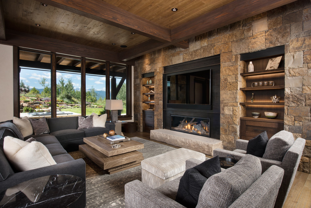This is an example of a large country open concept family room in Denver with a home bar, beige walls, medium hardwood floors, a metal fireplace surround, a wall-mounted tv, brown floor and a ribbon fireplace.