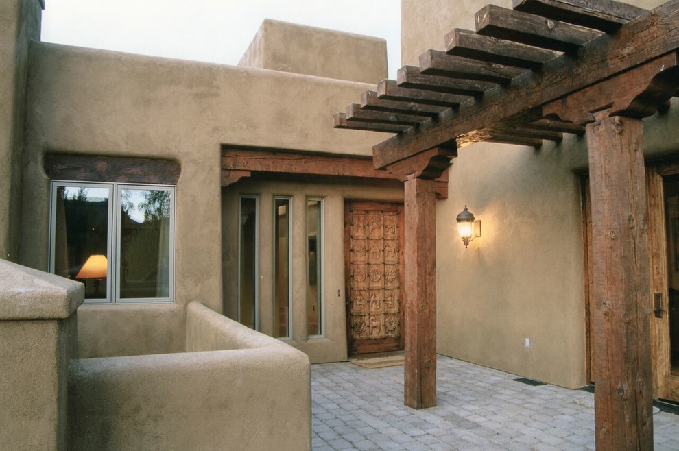 This is an example of a mid-sized two-storey stucco brown exterior in Other with a flat roof.