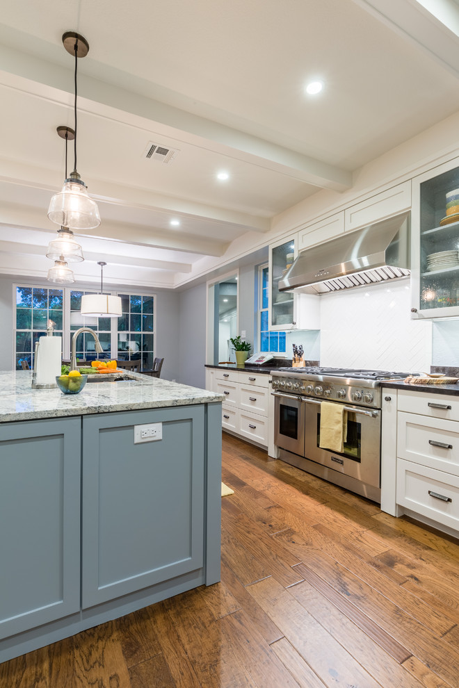 Example of a large transitional l-shaped medium tone wood floor open concept kitchen design in Austin with a double-bowl sink, recessed-panel cabinets, gray cabinets, granite countertops, white backsplash, ceramic backsplash, stainless steel appliances and an island