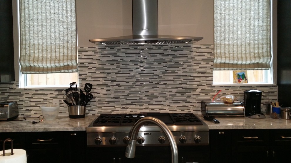 Large transitional l-shaped dark wood floor and brown floor open concept kitchen photo in Houston with an undermount sink, dark wood cabinets, granite countertops, gray backsplash, matchstick tile backsplash, stainless steel appliances and an island
