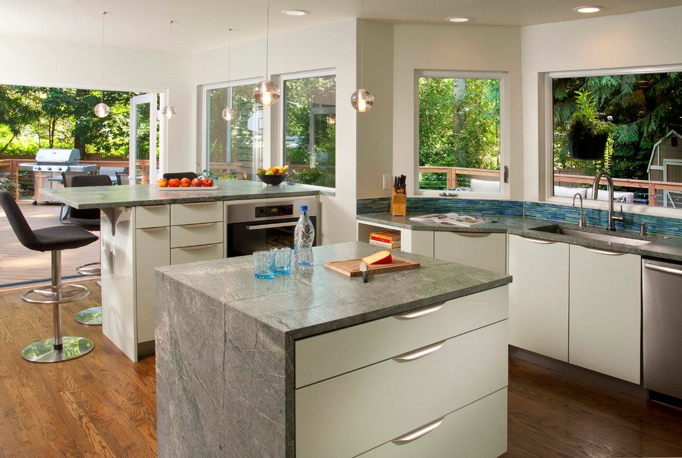 Inspiration for a large contemporary kitchen pantry in Seattle with an undermount sink, flat-panel cabinets, green cabinets, granite benchtops, blue splashback, mosaic tile splashback, stainless steel appliances, dark hardwood floors and with island.
