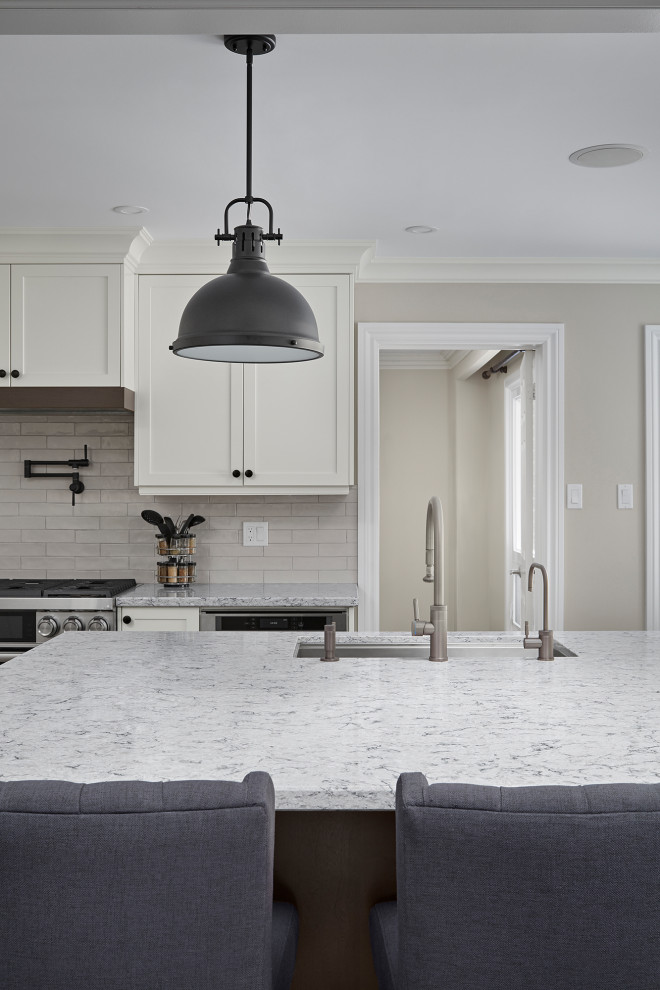 Example of an u-shaped eat-in kitchen design in Toronto with an undermount sink, shaker cabinets, white cabinets, quartz countertops, white backsplash, subway tile backsplash, stainless steel appliances, an island and gray countertops
