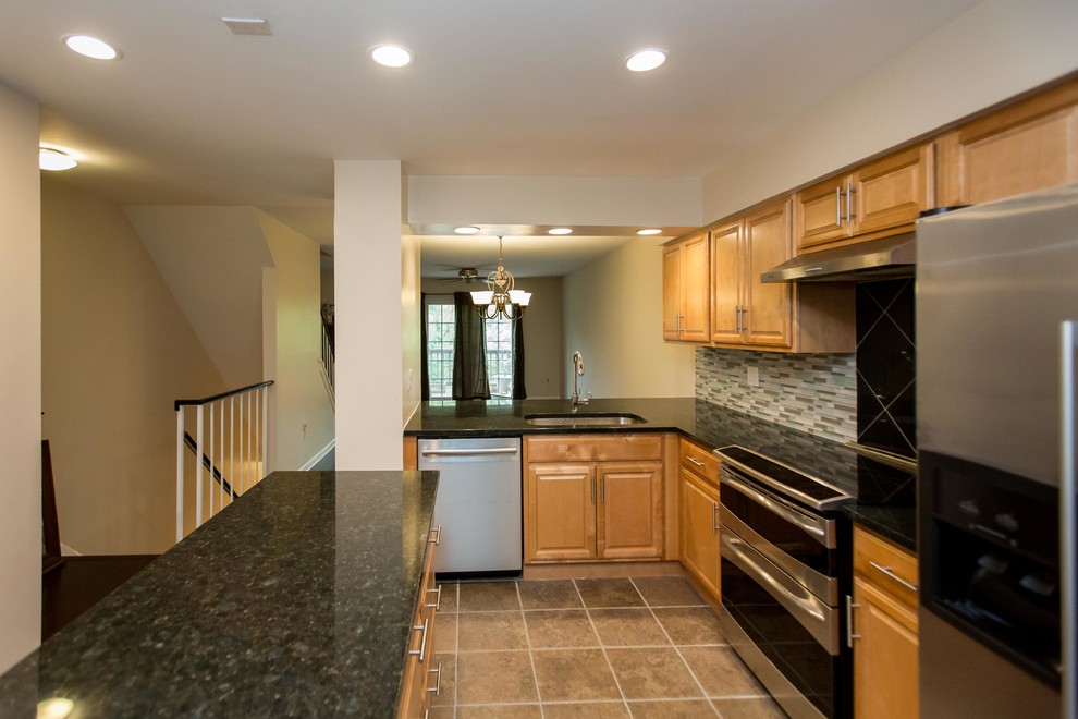 Mid-sized elegant galley ceramic tile and brown floor enclosed kitchen photo in DC Metro with an undermount sink, raised-panel cabinets, light wood cabinets, granite countertops, gray backsplash, matchstick tile backsplash, stainless steel appliances, two islands and black countertops