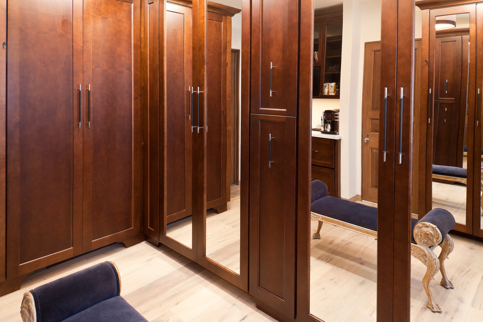 Photo of a traditional dressing room in Baltimore with recessed-panel cabinets, dark wood cabinets and light hardwood floors.