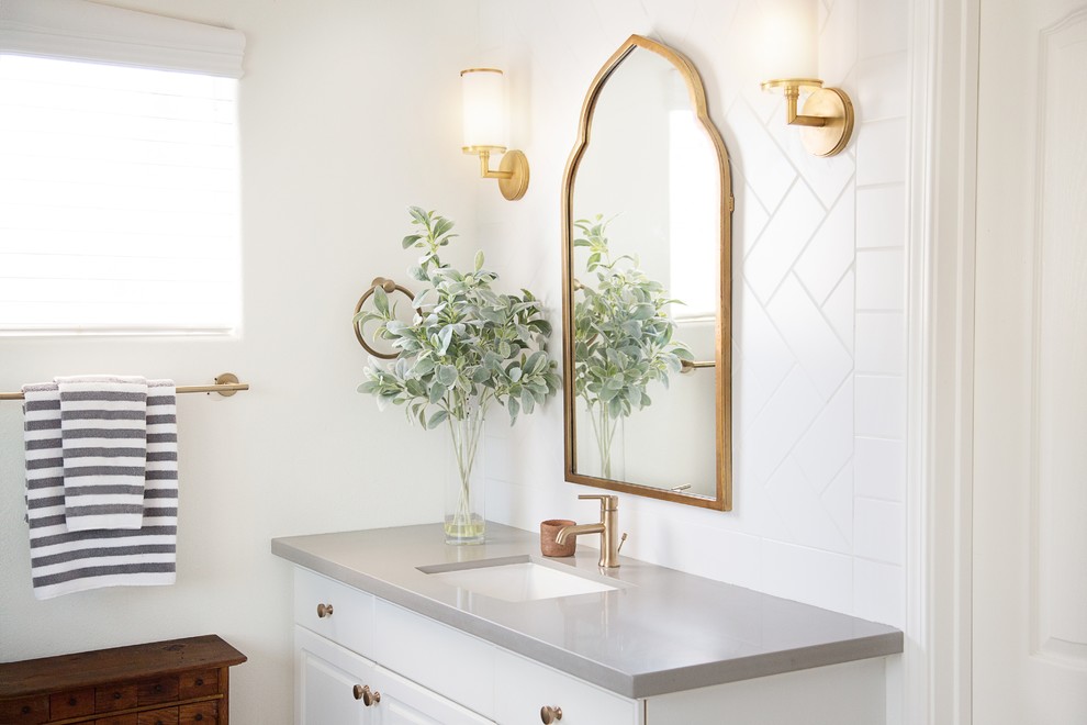 Mid-sized transitional 3/4 white tile and porcelain tile alcove shower photo with raised-panel cabinets, white cabinets, a two-piece toilet, white walls, an undermount sink, solid surface countertops and a hinged shower door